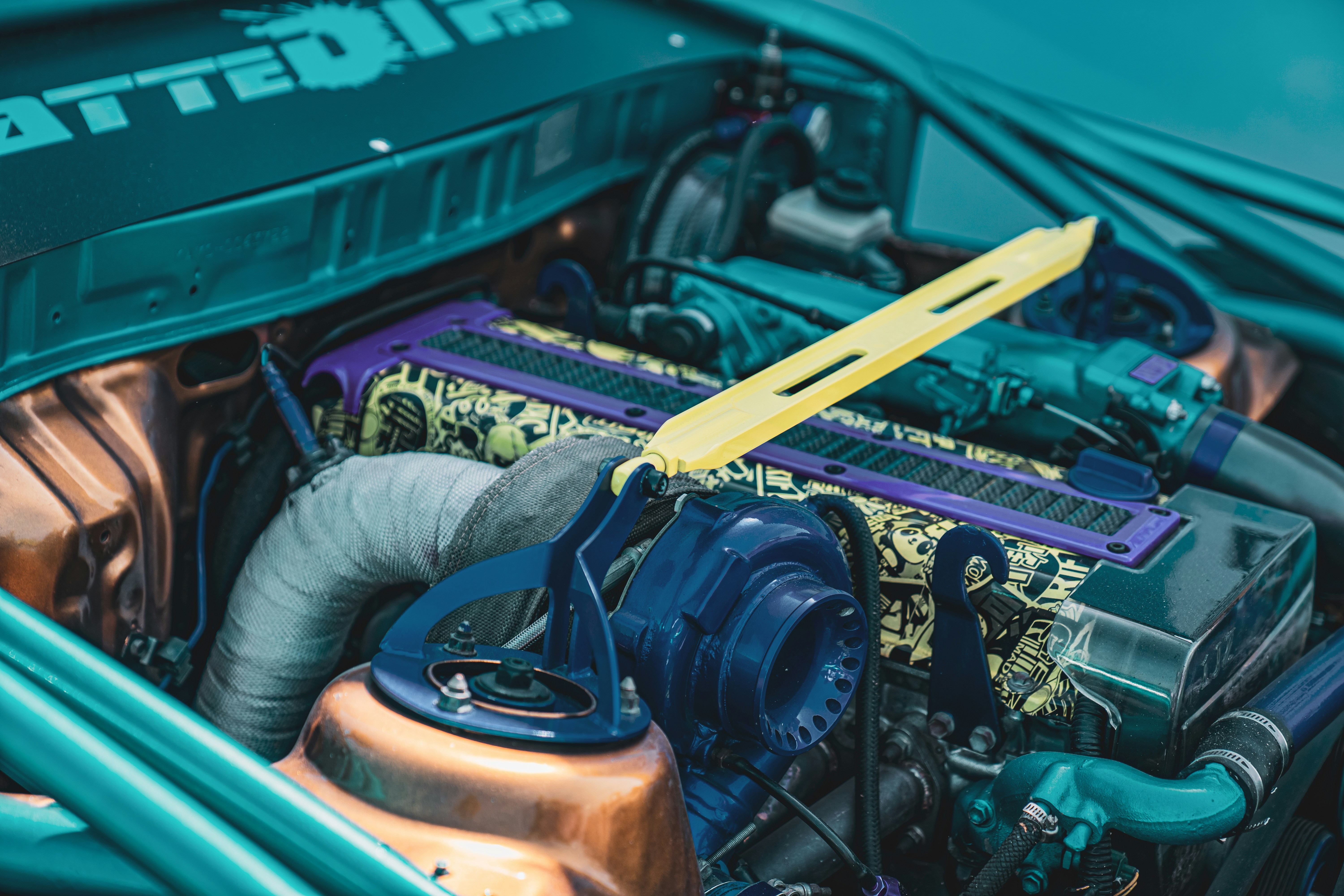 Engine bay with turbocharger and performance parts in dimly lit workshop, orange accent lighting