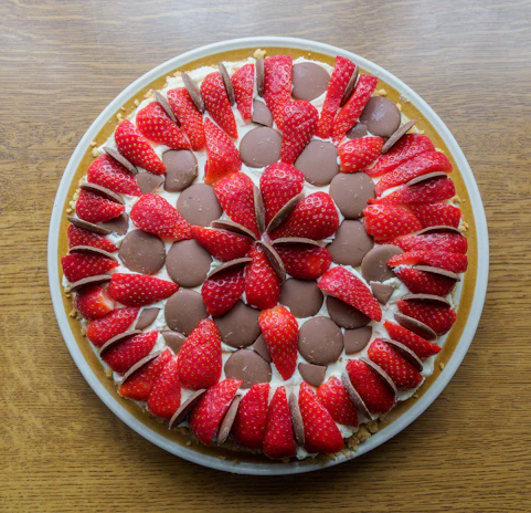 An elegant chocolate cake with smooth ganache and fresh strawberries arranged on top