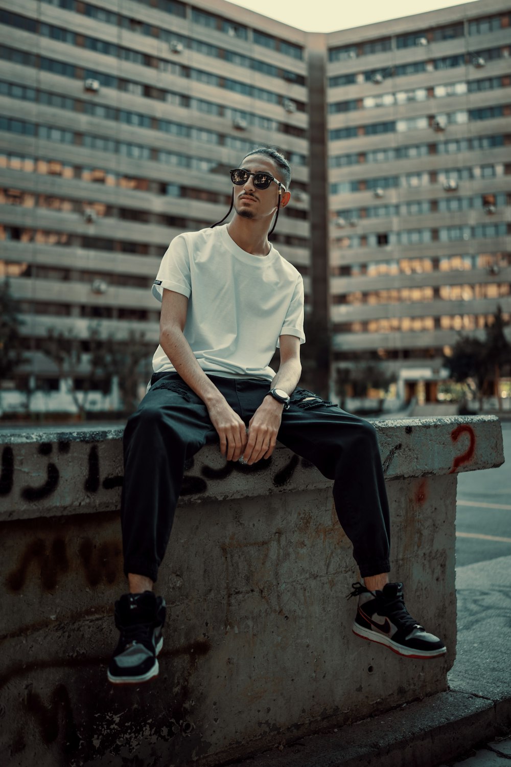 a man sitting on a ledge in front of a building