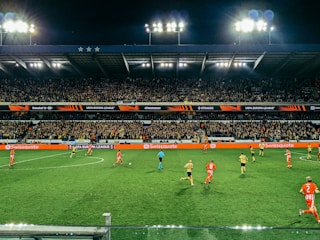 A vibrant soccer match in progress under stadium lights with cheering fans.