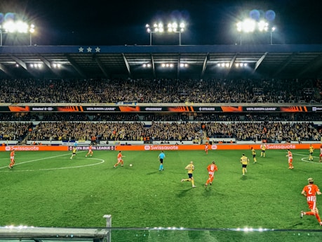A vibrant soccer match in progress under stadium lights with cheering fans.