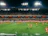 A lively youth soccer match captured under bright stadium lights, with families cheering in the stands.