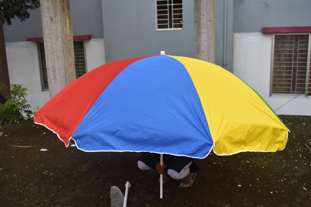 a person under a rainbow colored umbrella on the ground