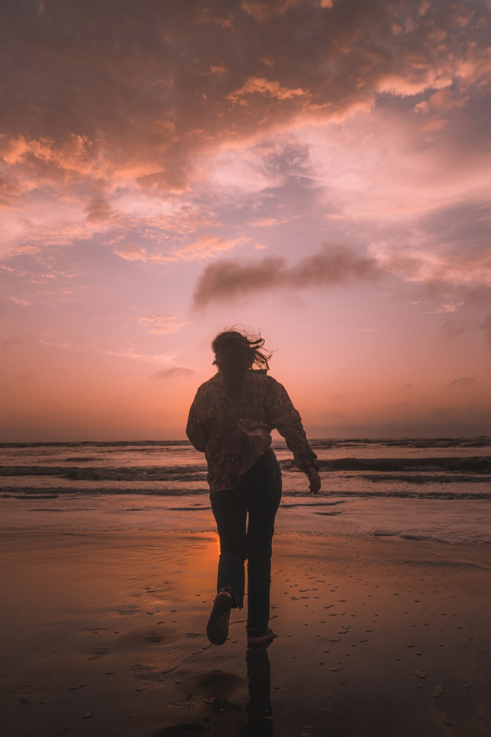 a woman is running on the beach at sunset