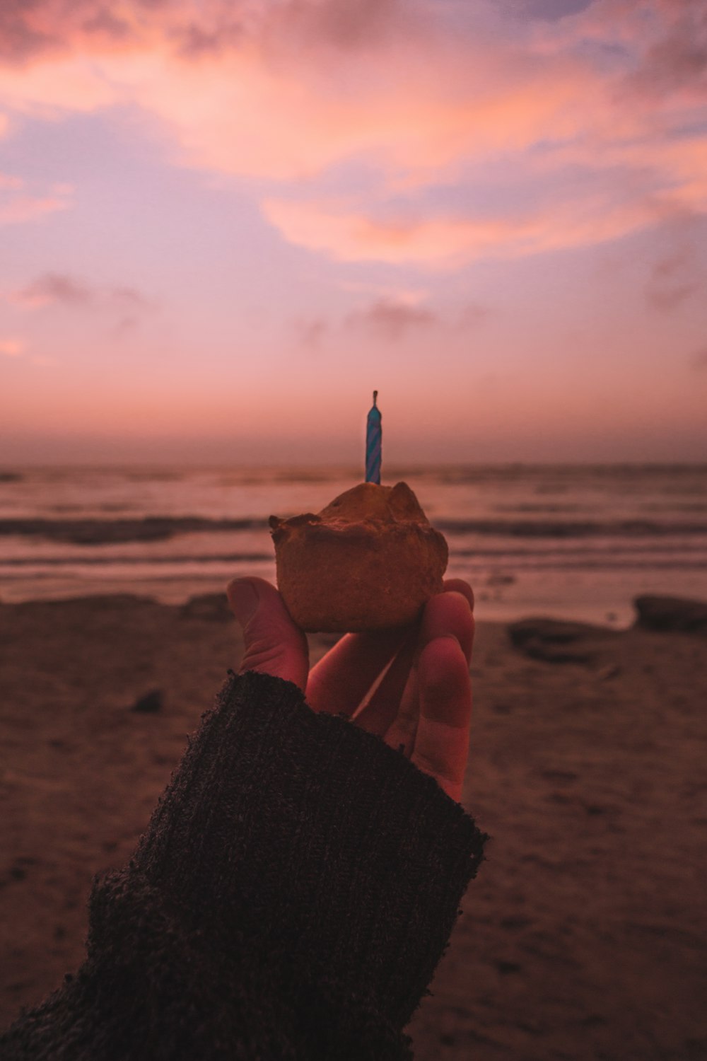 a person holding up a piece of food on a beach