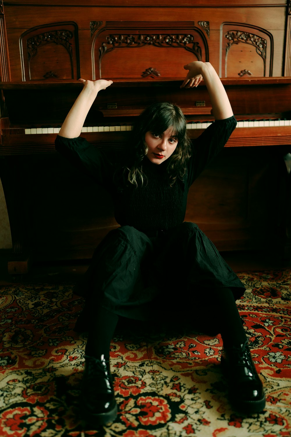 a woman sitting on the floor in front of a piano