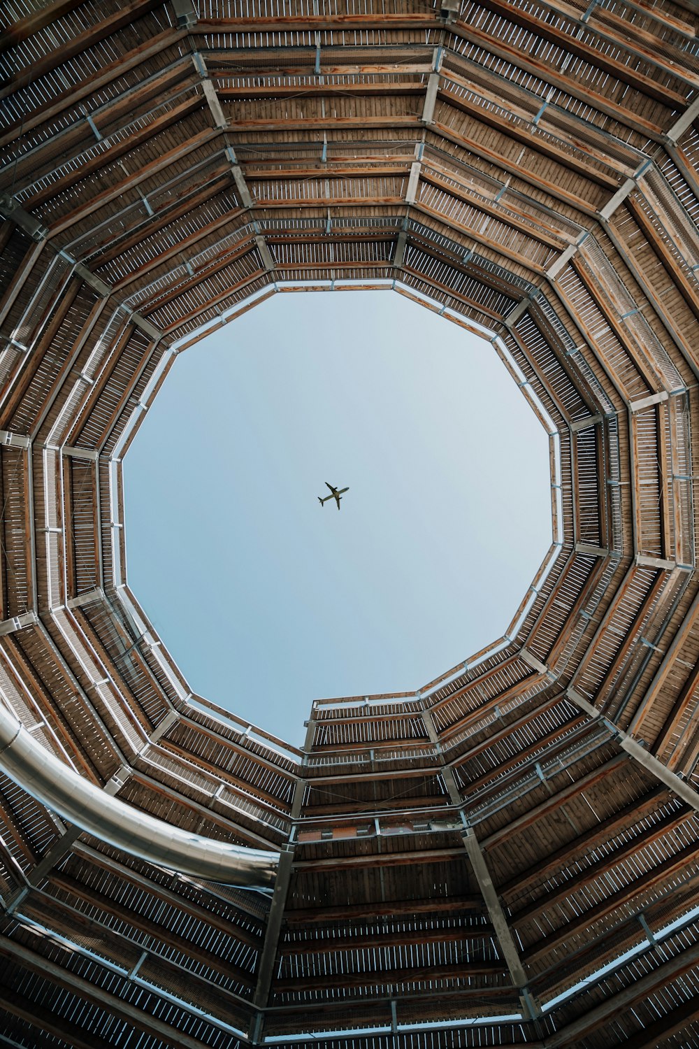 an airplane flying in the sky through a wooden structure