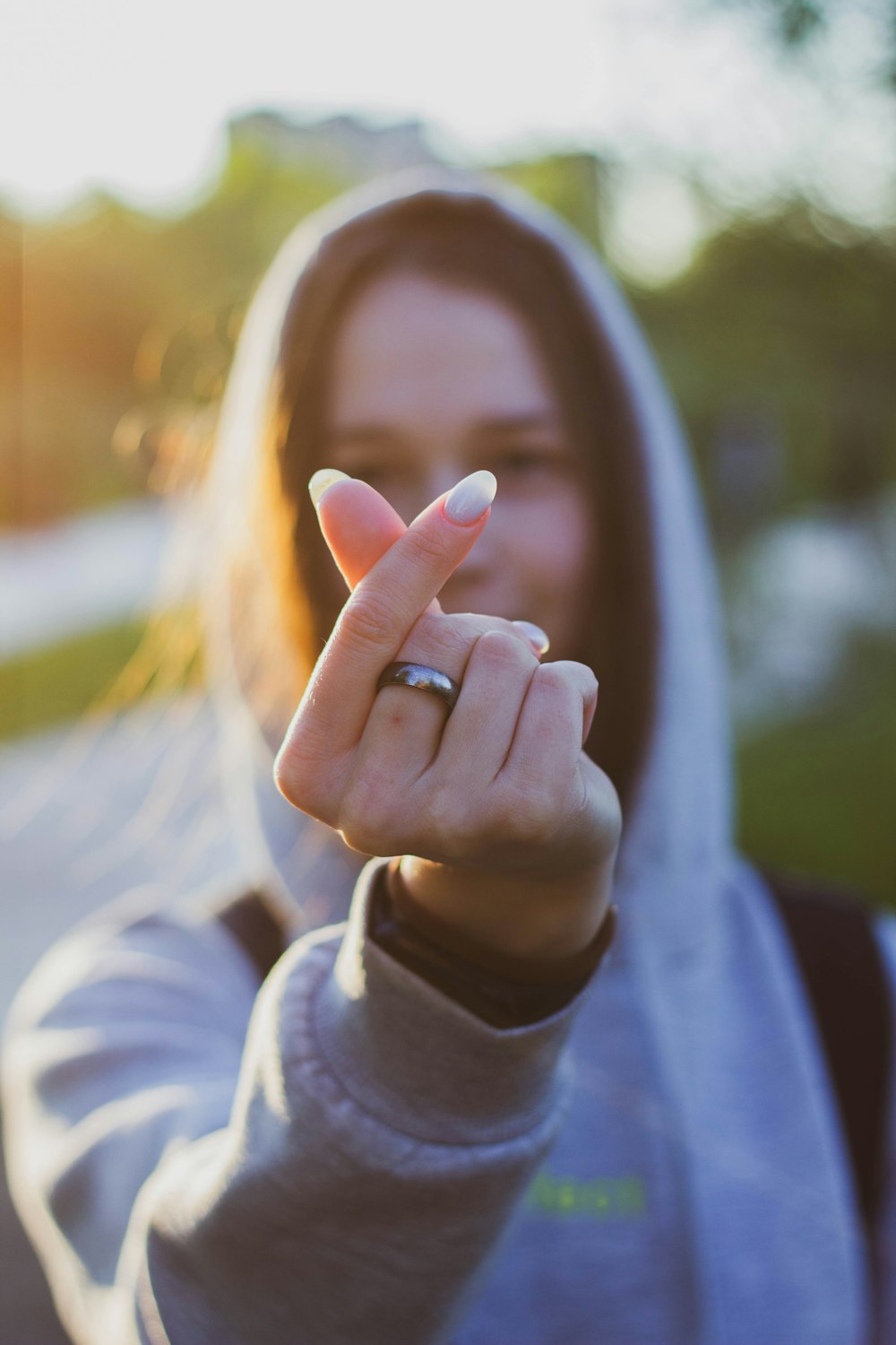 a woman in a hoodie is holding her finger up