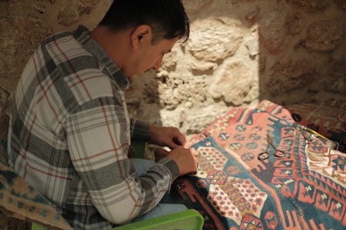 A craftsman carefully inspecting a piece of fine fabric under natural light.
