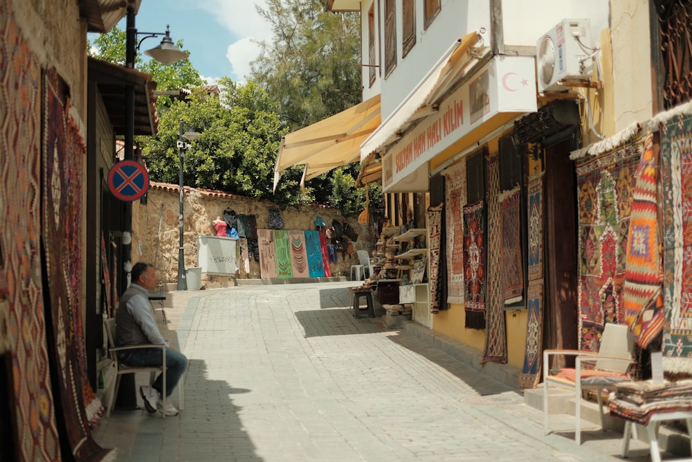 a person sitting on a chair in a narrow street