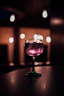 Close-up of a steaming, dark purple cocktail glowing under a ghostly light.