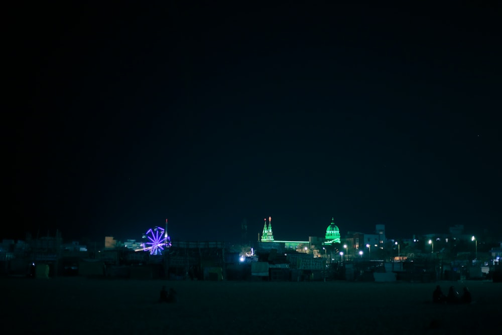 a city at night with a ferris wheel in the foreground