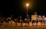 Group of kids wearing colorful protective gear practicing skating drills in a park