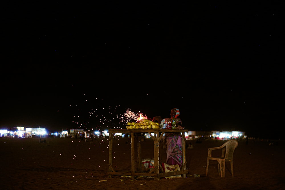 a person sitting at a table with fireworks in the background