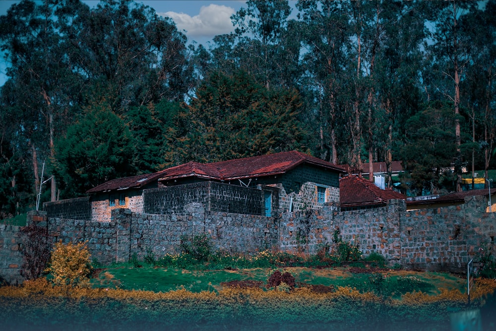 a stone wall with a red roof next to a body of water