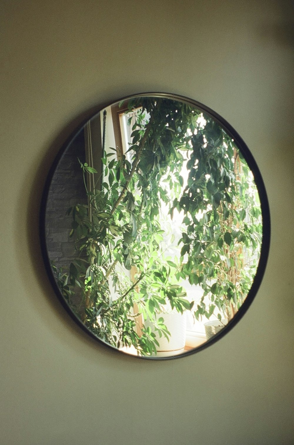 a round mirror hanging on the side of a wall