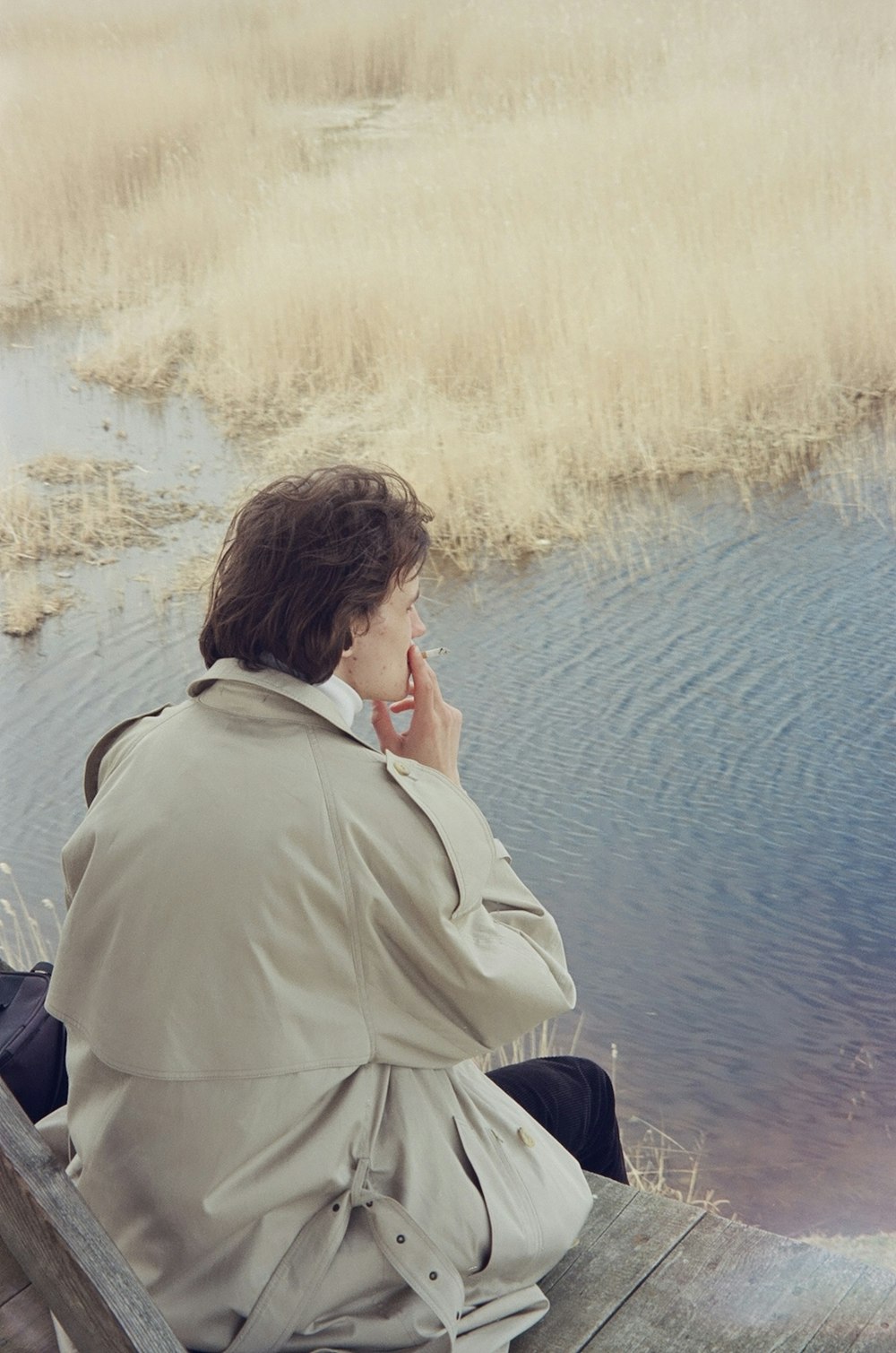 a woman sitting on a dock talking on a cell phone