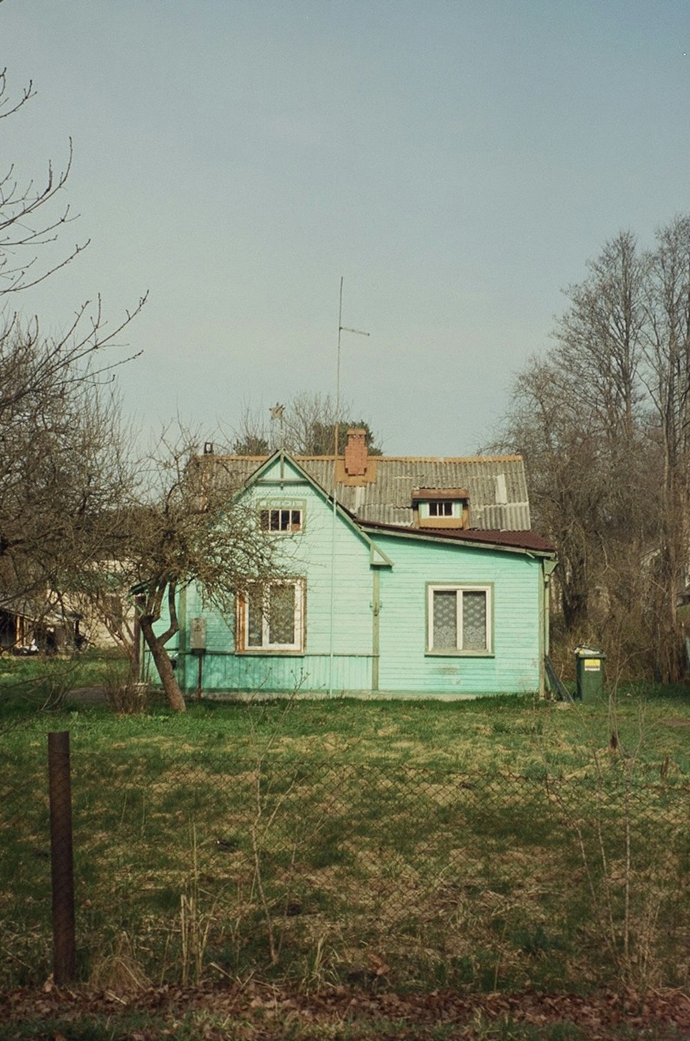 a blue house sitting in the middle of a field