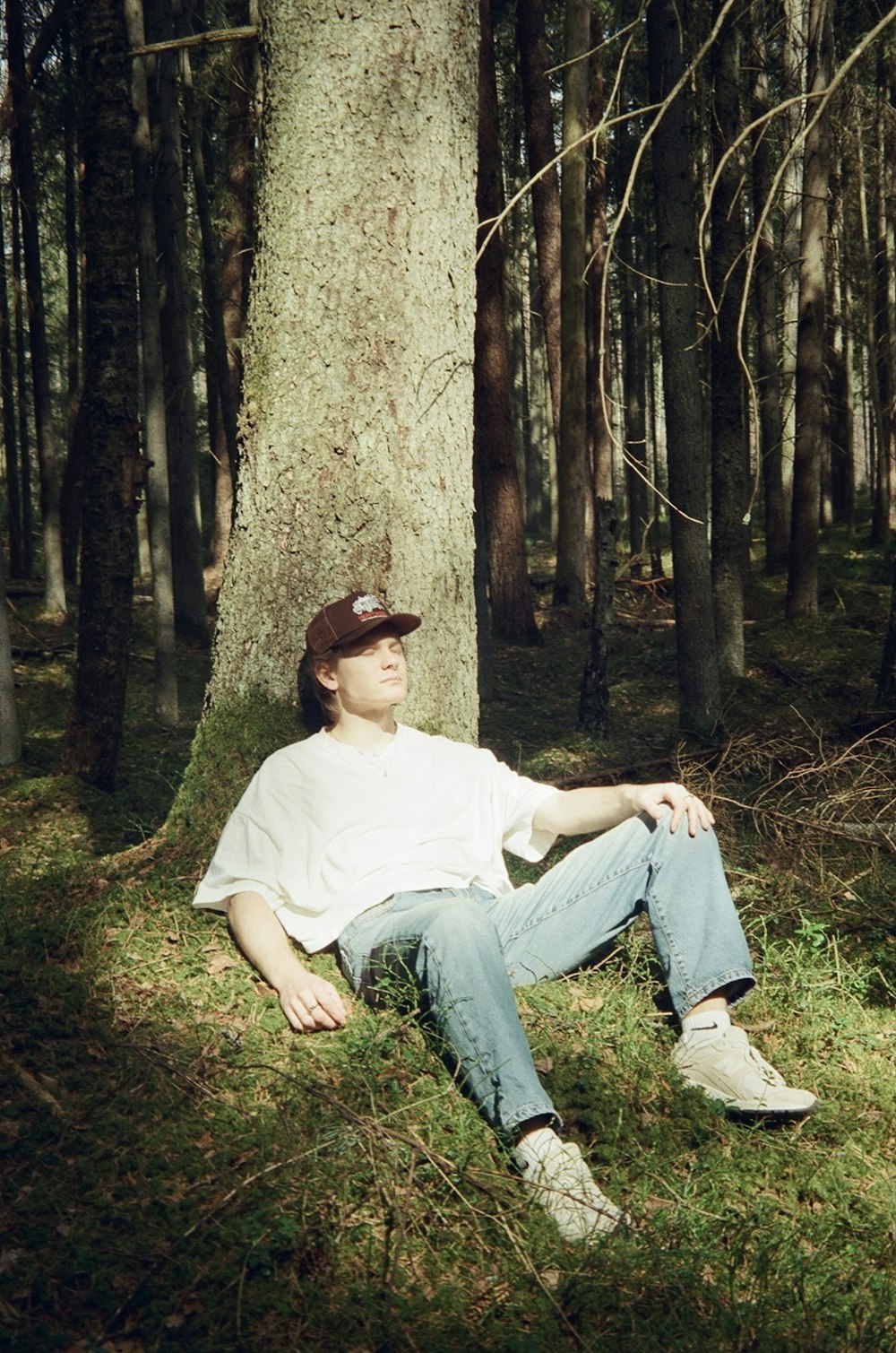 a man sitting in the grass next to a tree