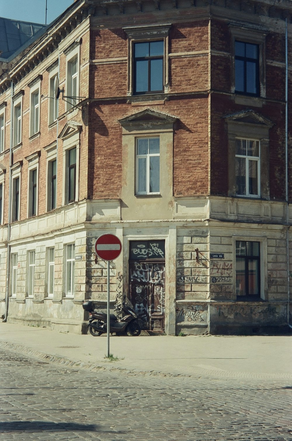 높은 벽돌 건물 앞에 앉아 있는 빨간 정지 표지판
