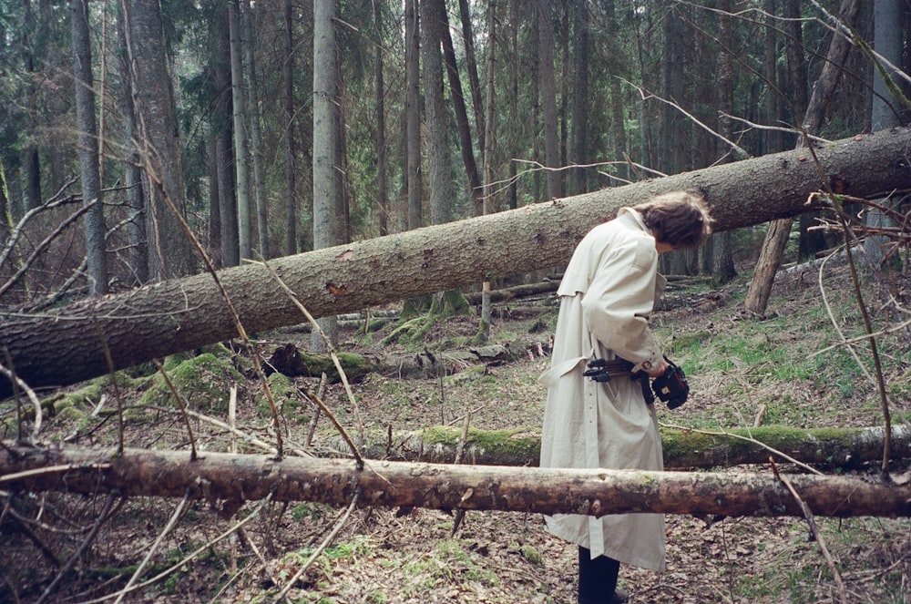 a woman in a white coat is standing in the woods