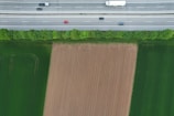 An aerial view of a truck moving along an interstate road surrounded by greenery.