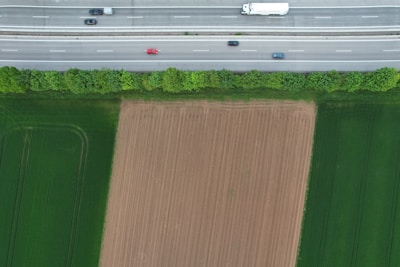 An aerial view of a truck moving along an interstate road surrounded by greenery.
