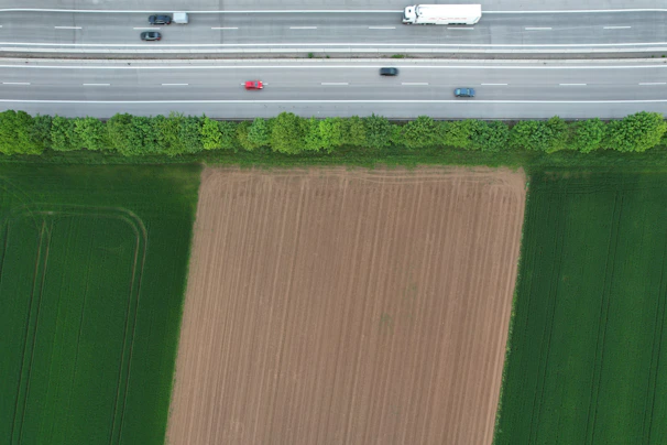 Aerial view of multiple trucks moving along a highway surrounded by green fields.