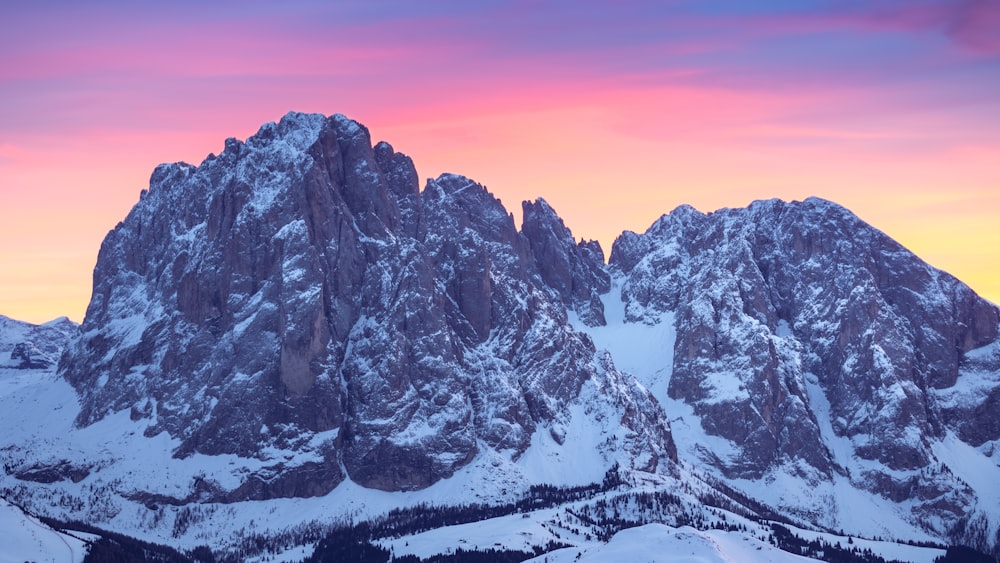 a mountain range covered in snow at sunset