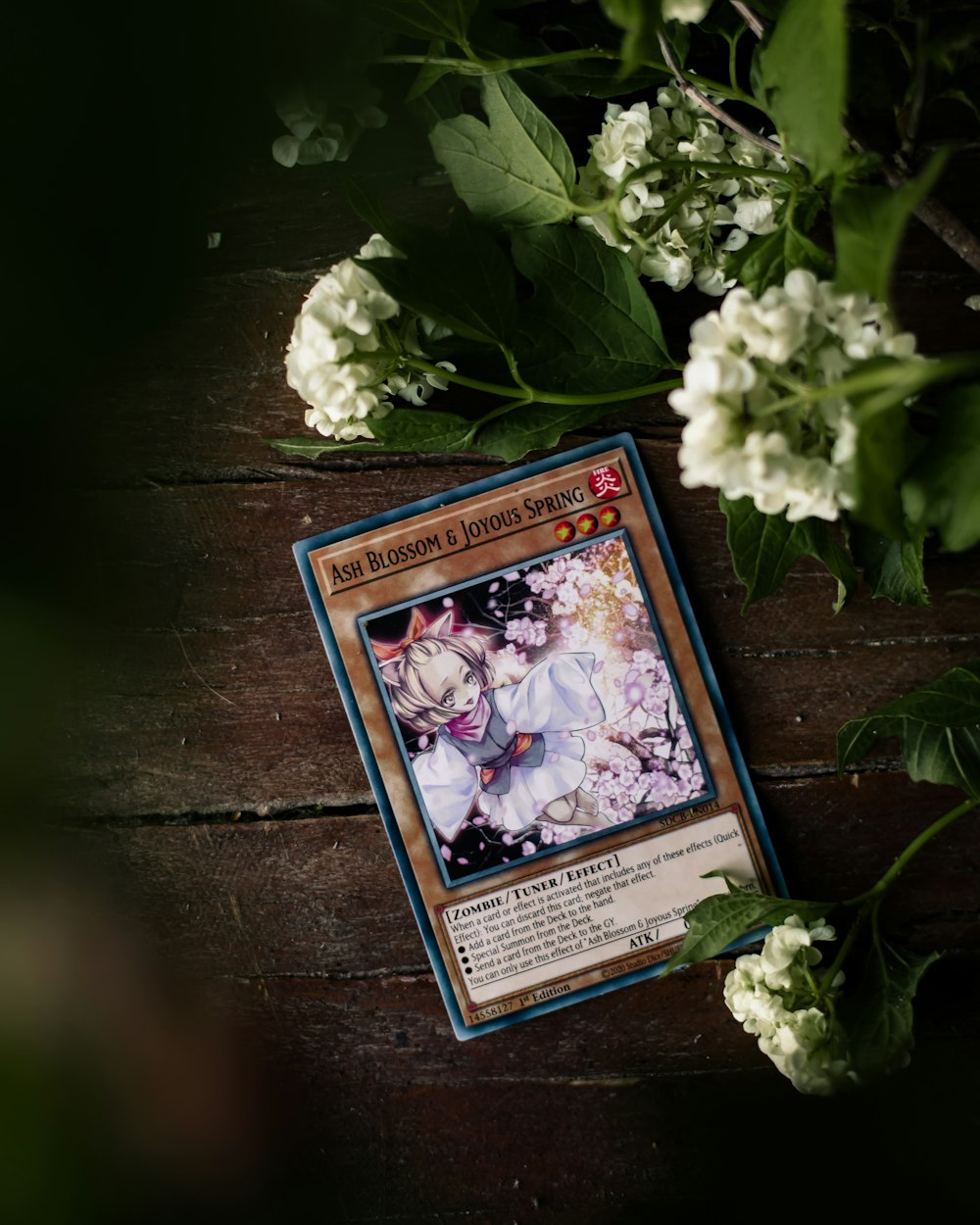 a card sitting on top of a wooden table next to flowers