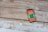 A smartphone with a colorful screen displaying the text 'scan me for your feedback' and a QR code lies on a wooden surface. The planks of wood have a rustic look with visible grain and some peeling paint.