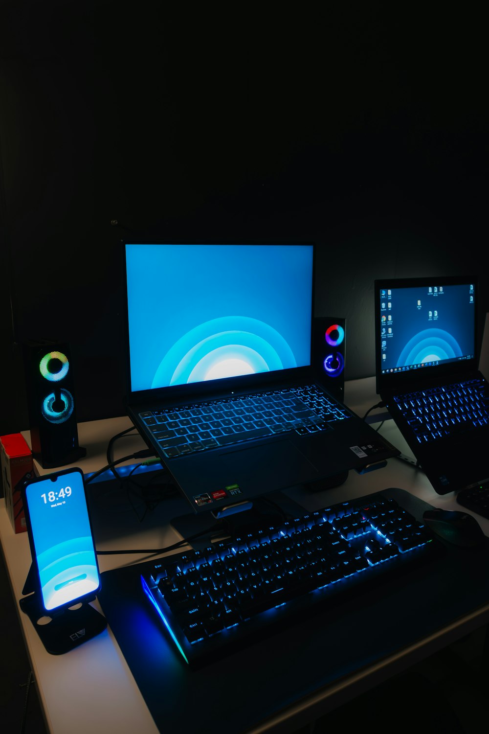 a desk with a laptop, monitor, keyboard and cell phone on it