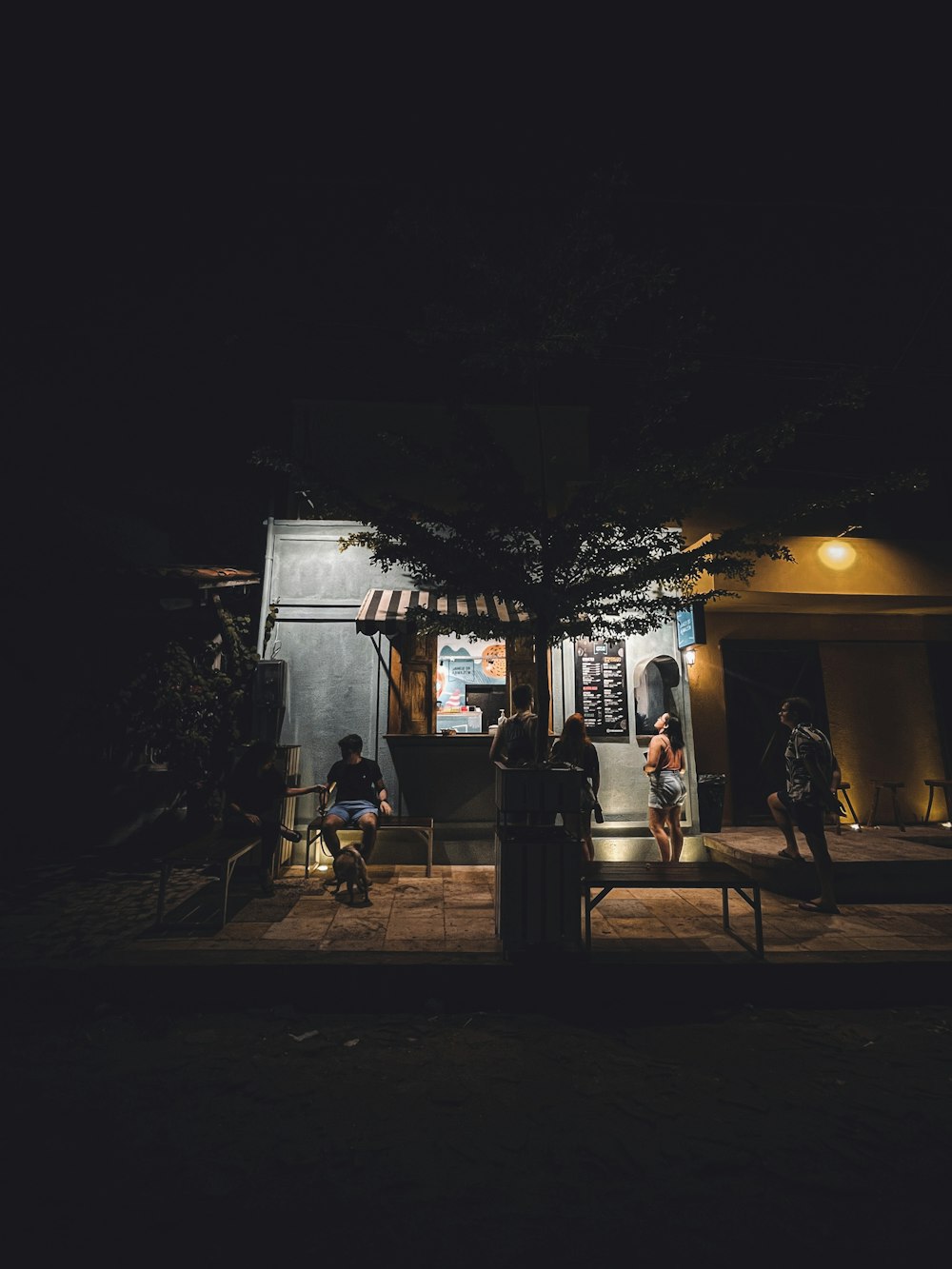 a group of people sitting outside of a building at night