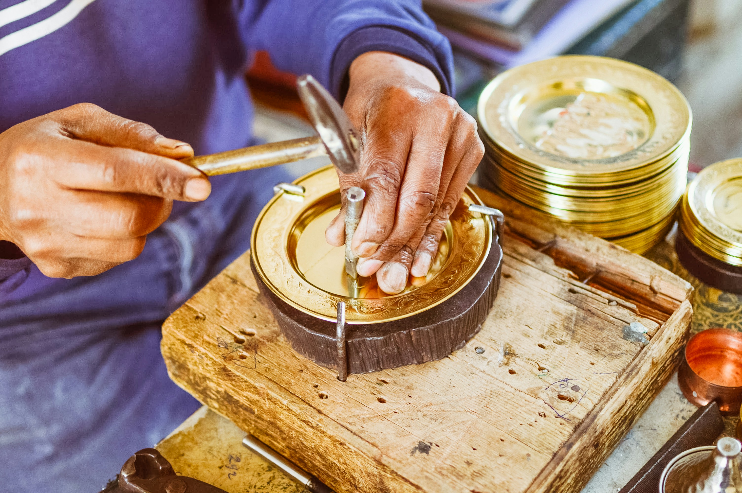 hands applying gold lacquer adhesive to a broken ceramic bowl for kintsugi repair