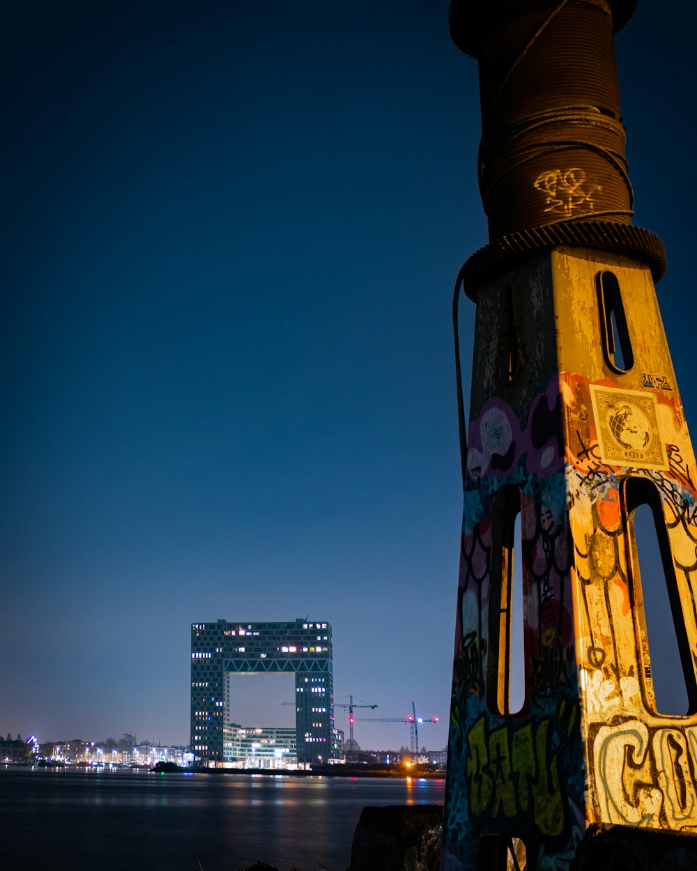 a tall tower with graffiti on it next to a body of water