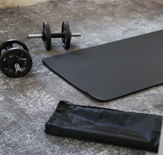 a pair of dumbbells and a black mat on the floor