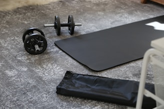 a pair of dumbbells and a black mat on the floor
