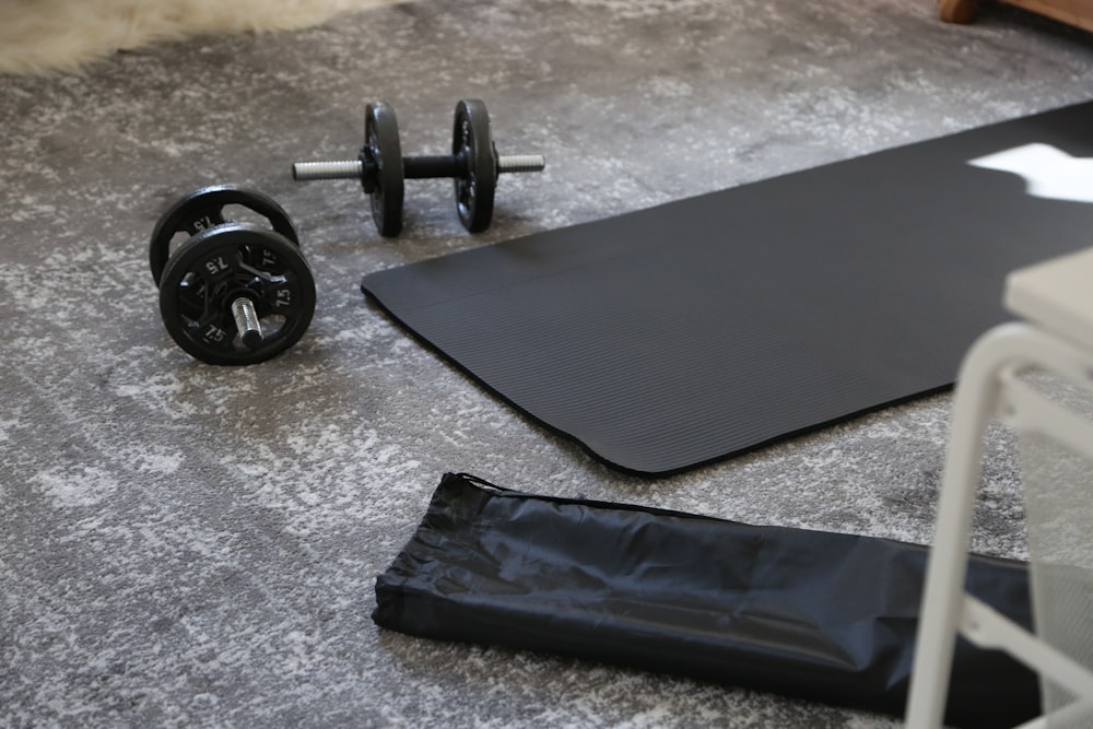 a pair of dumbbells and a black mat on the floor