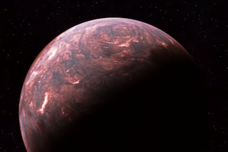 A detailed view of a planet with swirling, cloud-like formations in shades of brown, red, and pink. The right side of the planet is cast in shadow, creating a dramatic contrast with the illuminated portion. The surrounding space is vast and dark, dotted with faint, distant stars.