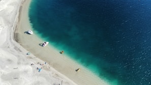 an aerial view of a beach with boats in the water