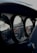 A close-up view of the dashboard in a car, focusing on the analog dials. The dials have black backgrounds with orange and white indicators, showing various measurements. The lighting suggests a dimly lit or shadowed environment, highlighting the curvature and material texture of the dashboard.