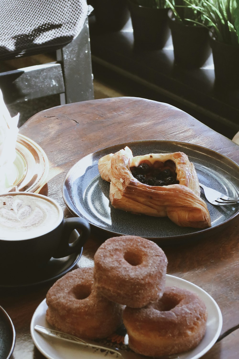 a wooden table topped with plates of doughnuts