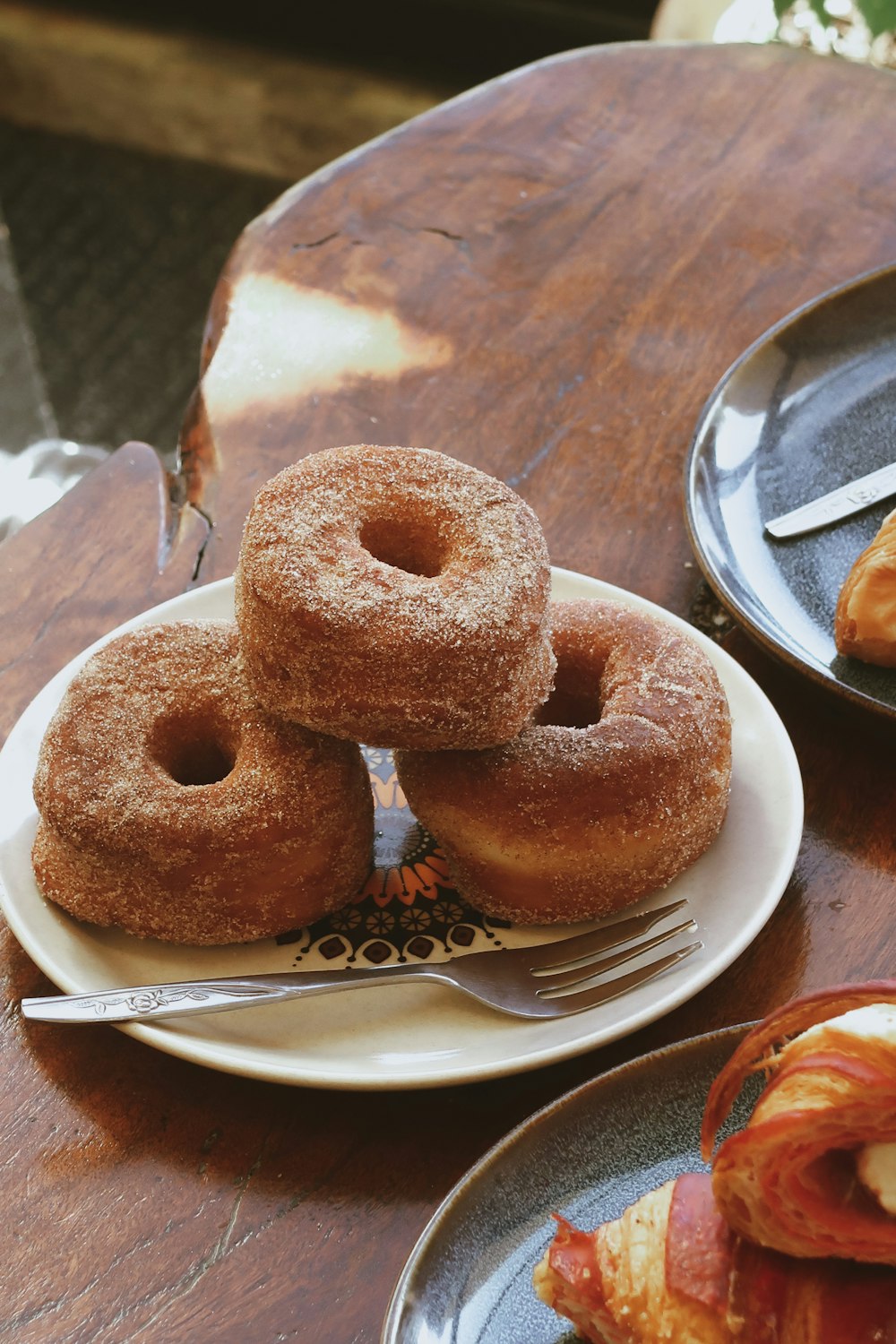 three donuts on a plate with a fork on a table