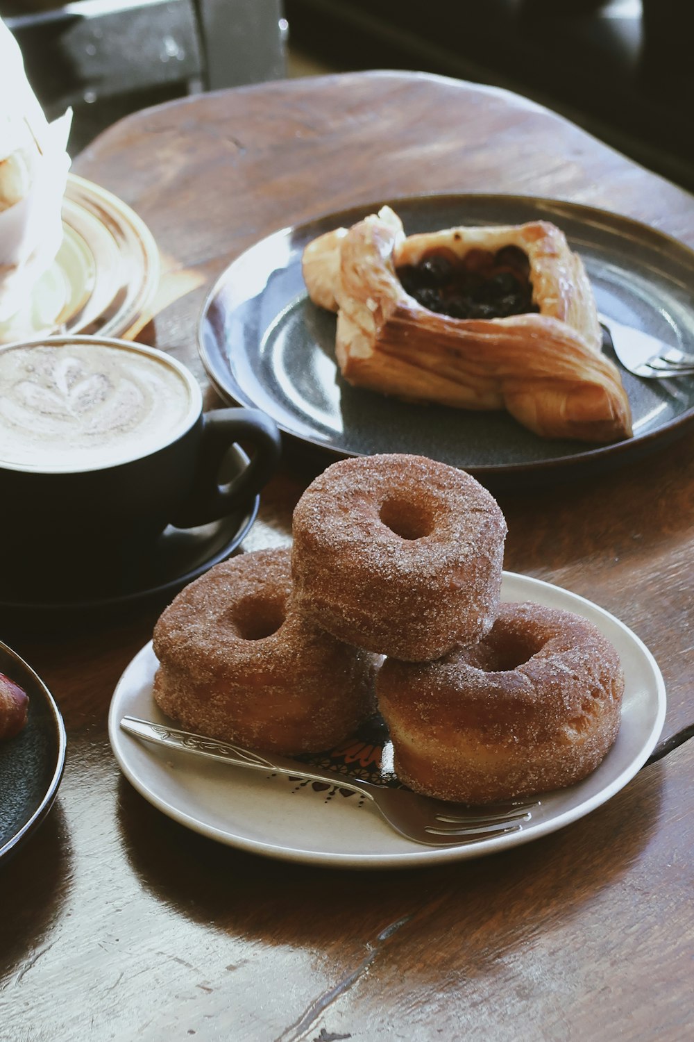 a wooden table topped with plates of donuts