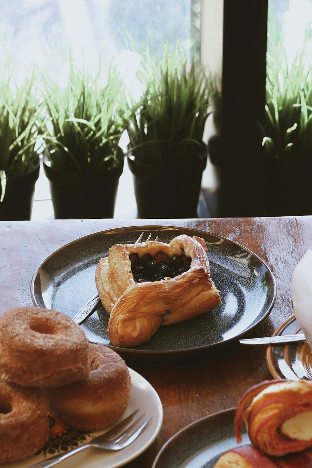 a table topped with plates of pastries and doughnuts