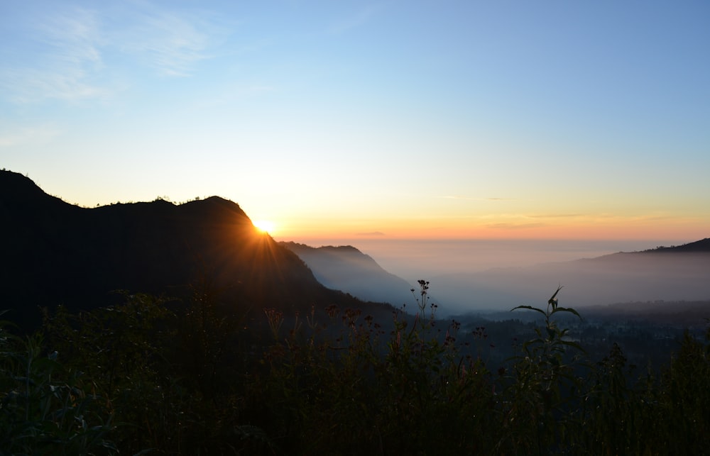 the sun is setting over a mountain range