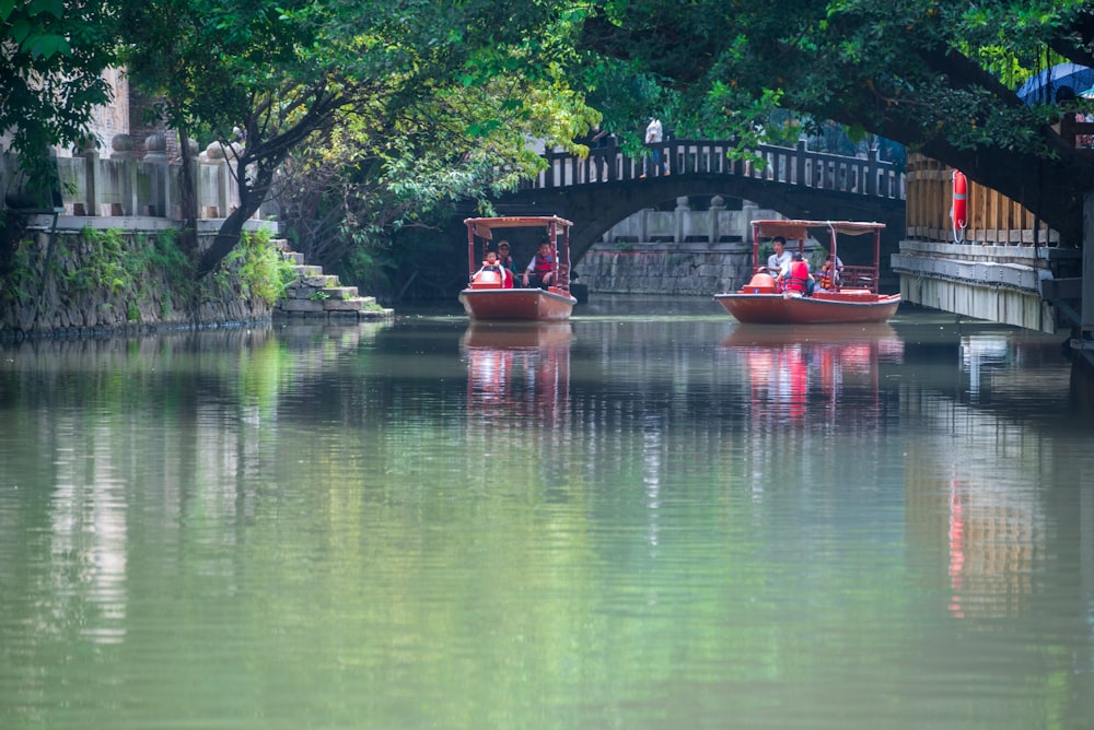 a couple of boats floating down a river next to a bridge