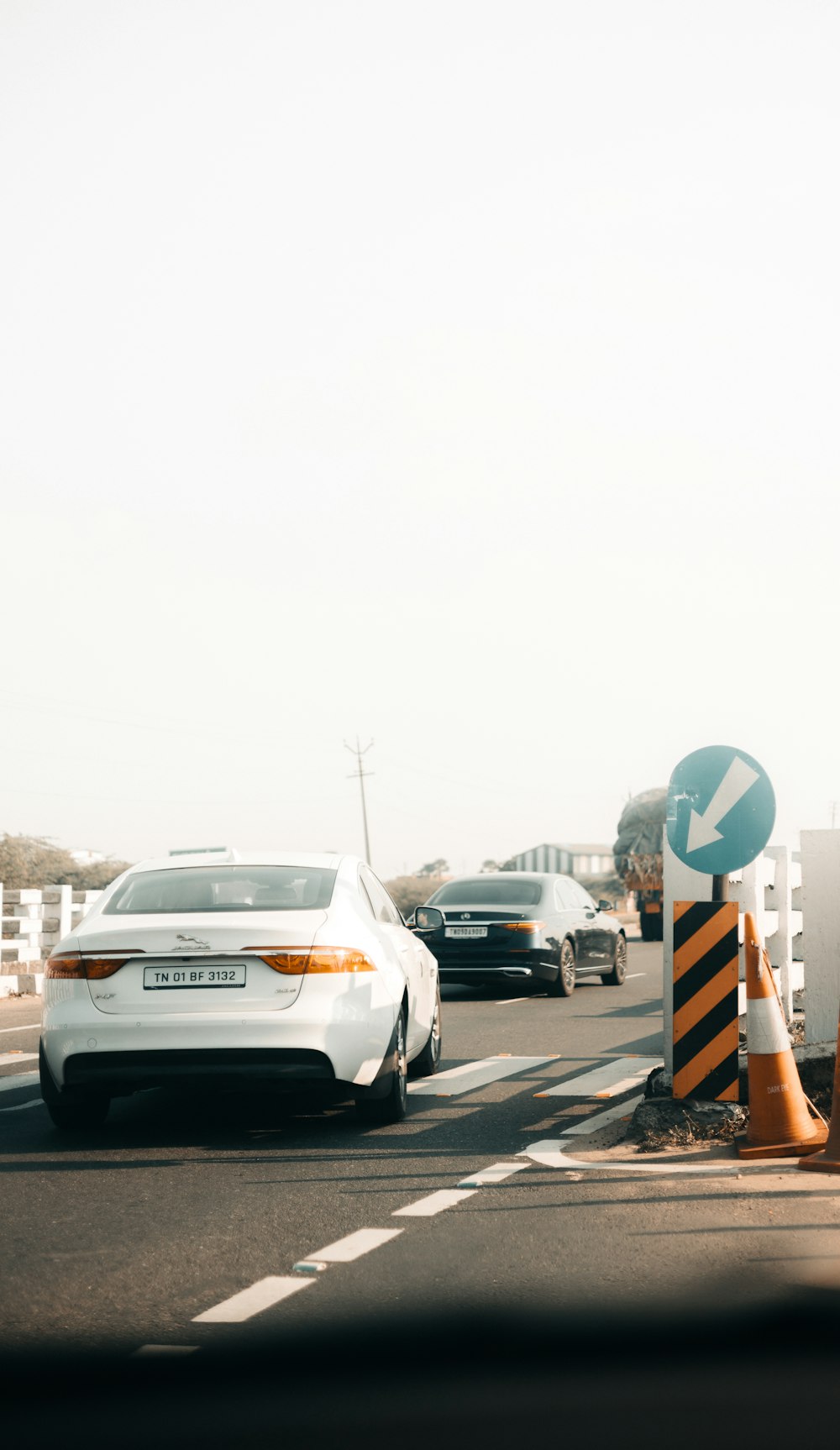 a white car driving down a street next to traffic cones