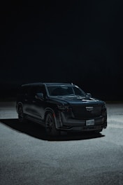 a black suv parked in a parking lot at night
