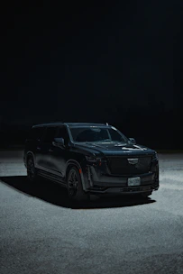 a black suv parked in a parking lot at night